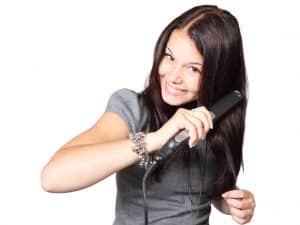 Lady using a titanium flat iron on her straight hair