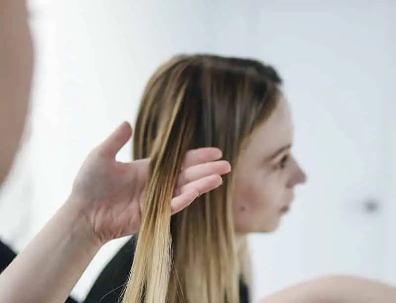 Person holding a woman's blonde straight hair