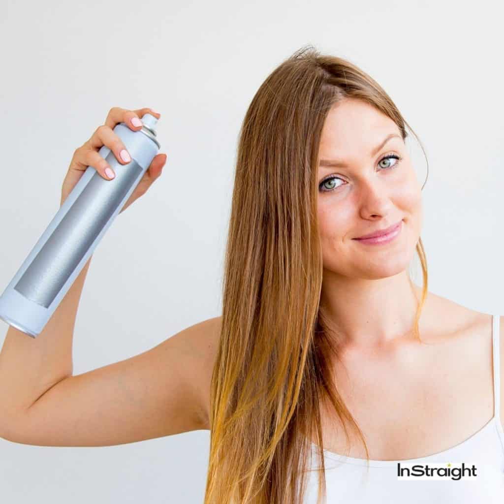 lady spraying dry shampoo to her hair
