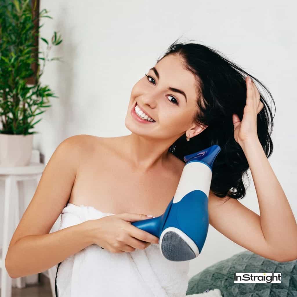 pretty girl drying her hair after shower (blow dryer vs hair dryer guide)