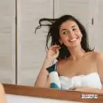 pretty girl blow drying hair in front of the mirror