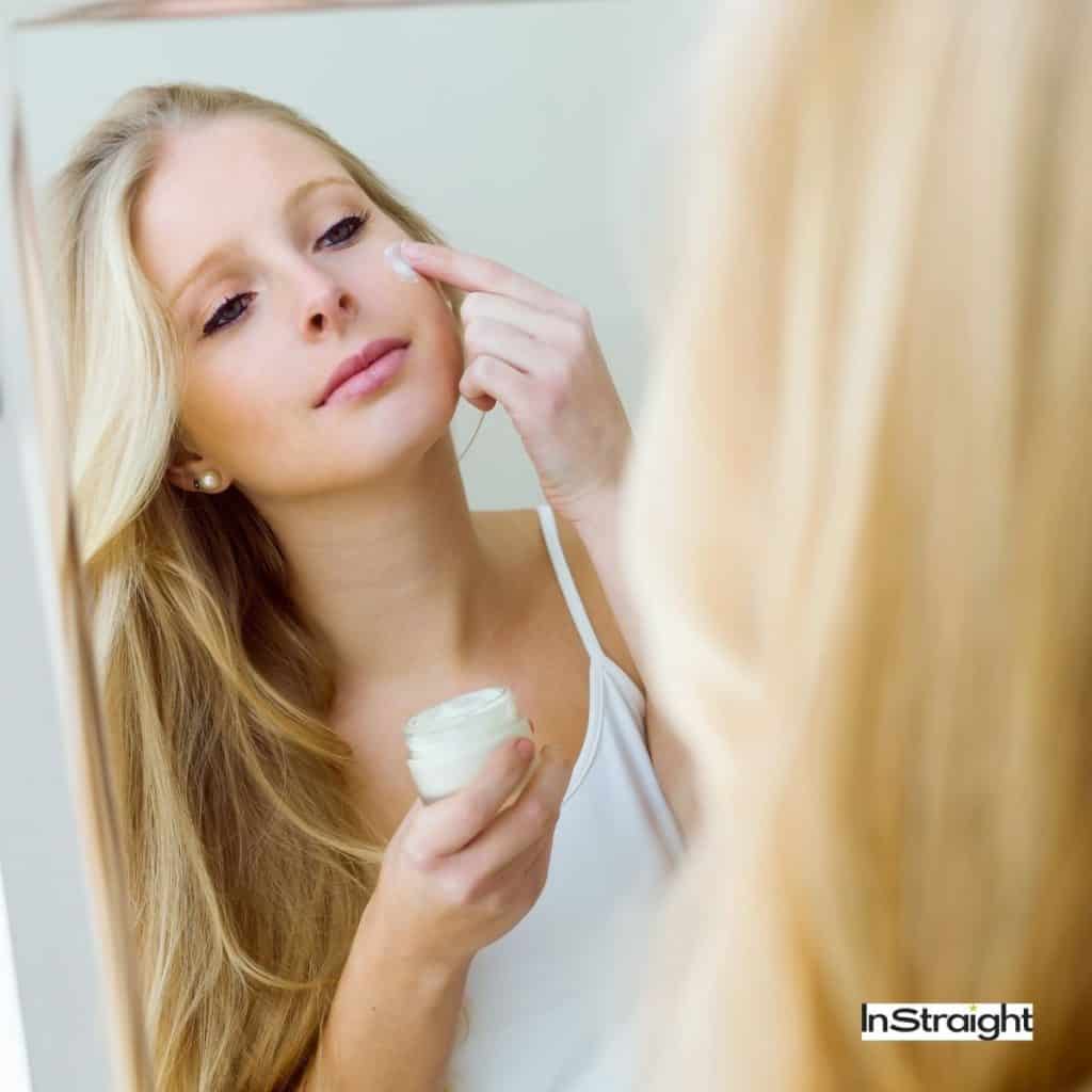 blonde woman putting a moisturizer