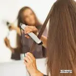 lady facing the mirror while using a hair straightener