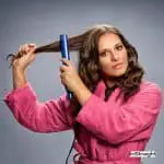 lady in pink robe using a flat iron but what is a hair straightener?