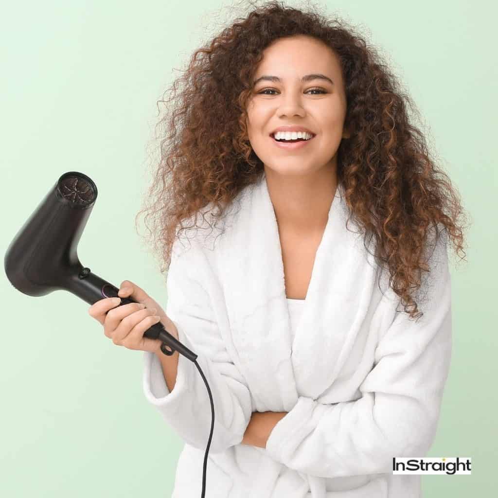 a curly-haired woman showing the difference between Blow Dryer Vs Hair Dryer