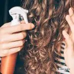 spraying heat protectant on a curly hair