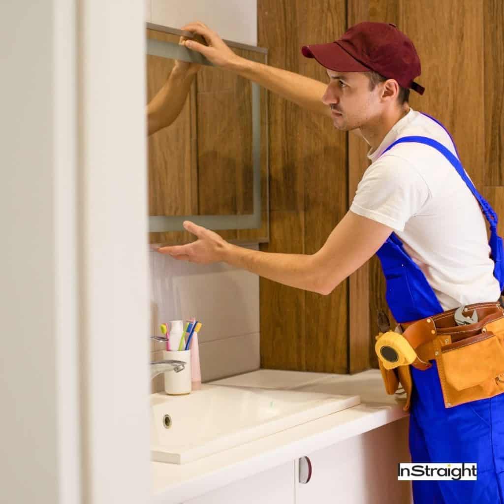 man installing a bathroom mirror