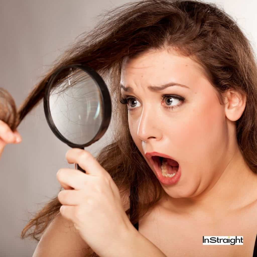 woman using a magnifying glass to check her damaged hair