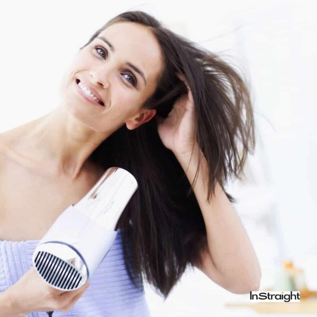 woman using a hair dryer and showing how to keep hair dryer cord from twisting