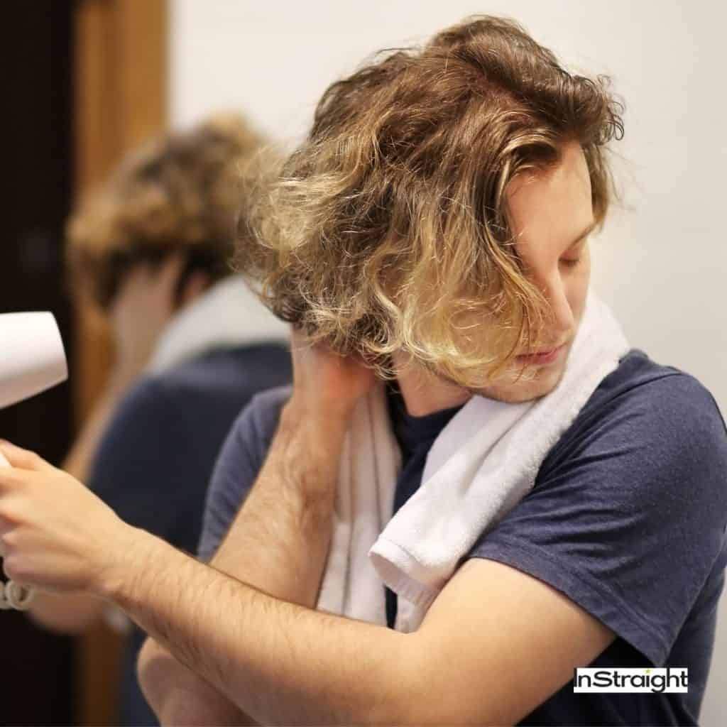 man blow drying his hair that causes damage