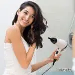 woman happily drying her hair using a low wattage hair dryer