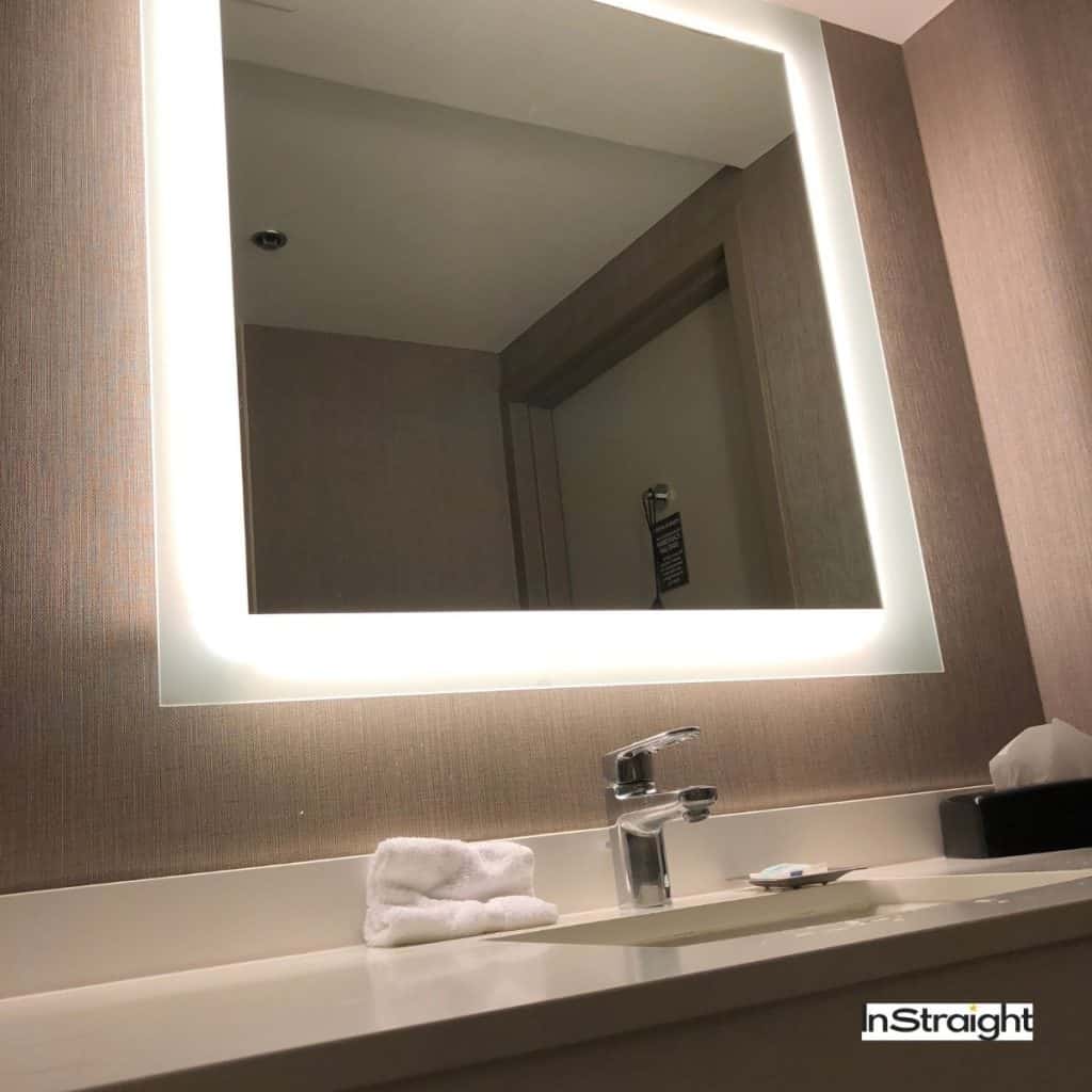 backlit mirror in a bathroom under title what's the difference between backlit mirrors and lighted mirrors?