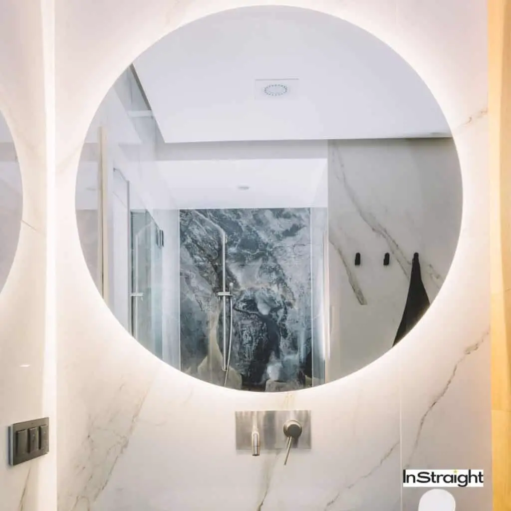 An elegant round lighted mirror under title What's the Difference Between Backlit And Lighted Mirrors